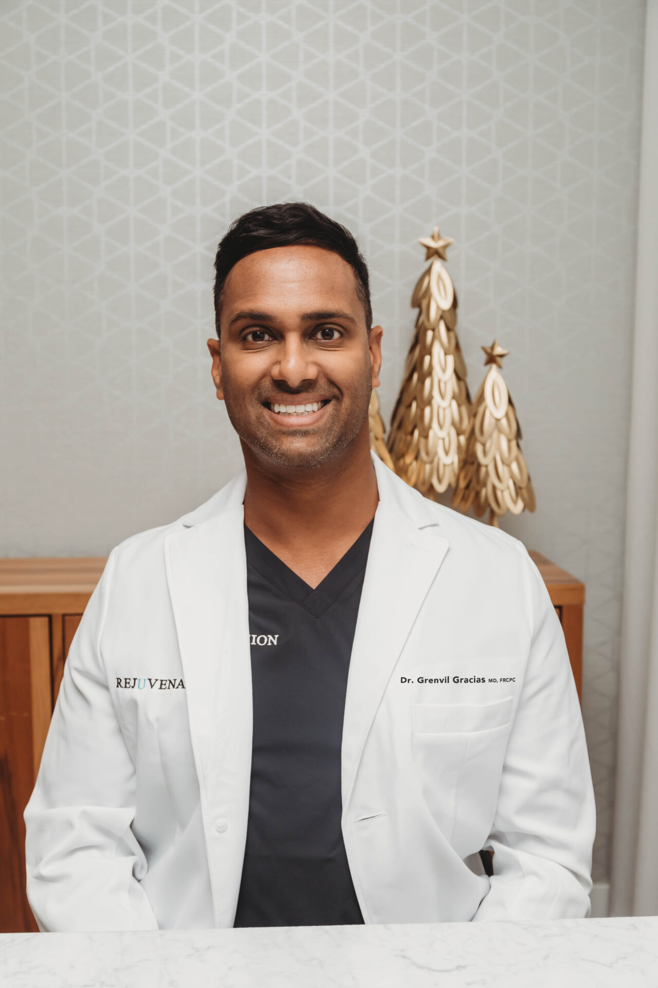 Dr. Gracias in a lab coat, smiling. 